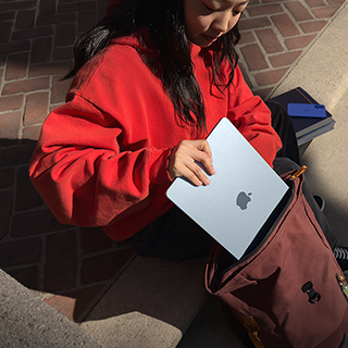 นักเรียนกำลังเก็บ MacBook Air ใส่ในกระเป๋าเป้