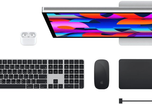 มุมมองด้านบนของอุปกรณ์เสริม Mac หลายชิ้น ได้แก่ Studio Display, Magic Keyboard, Magic Mouse, Magic Trackpad, AirPods และสายชาร์จ MagSafe